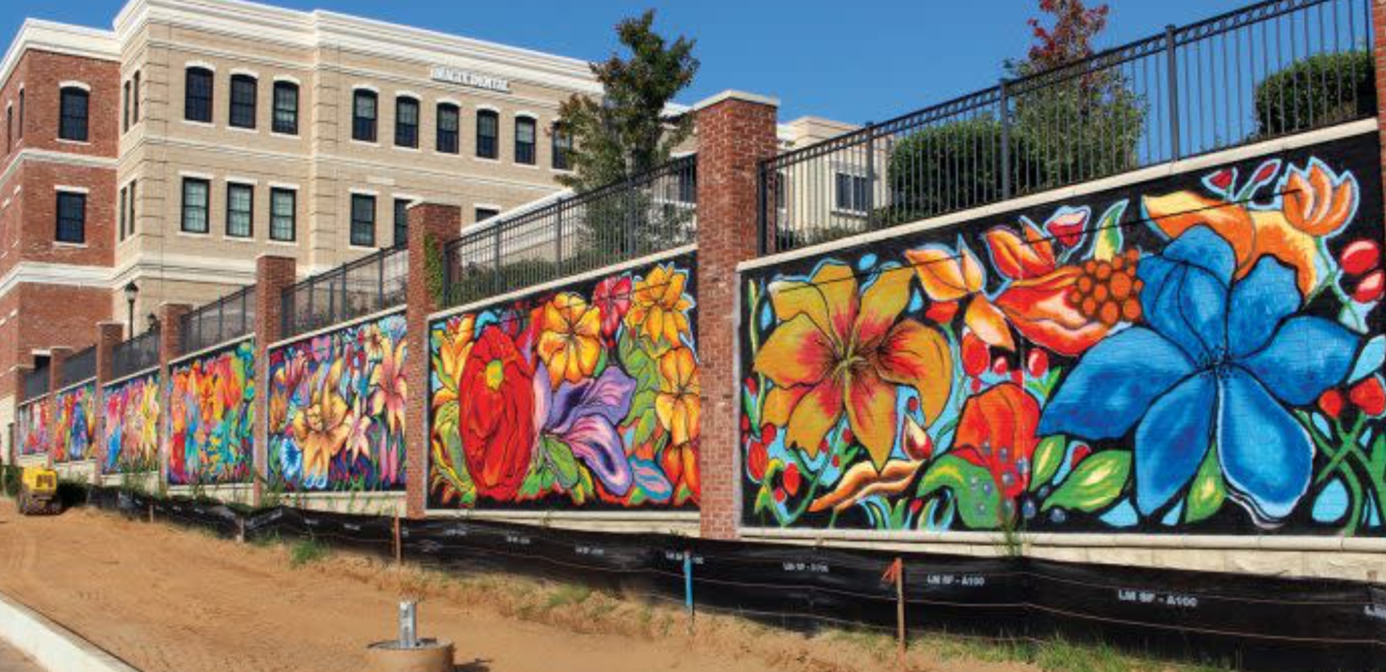 Large-scale floral mural painted across a long retaining wall by Atlanta muralist Corey Barksdale