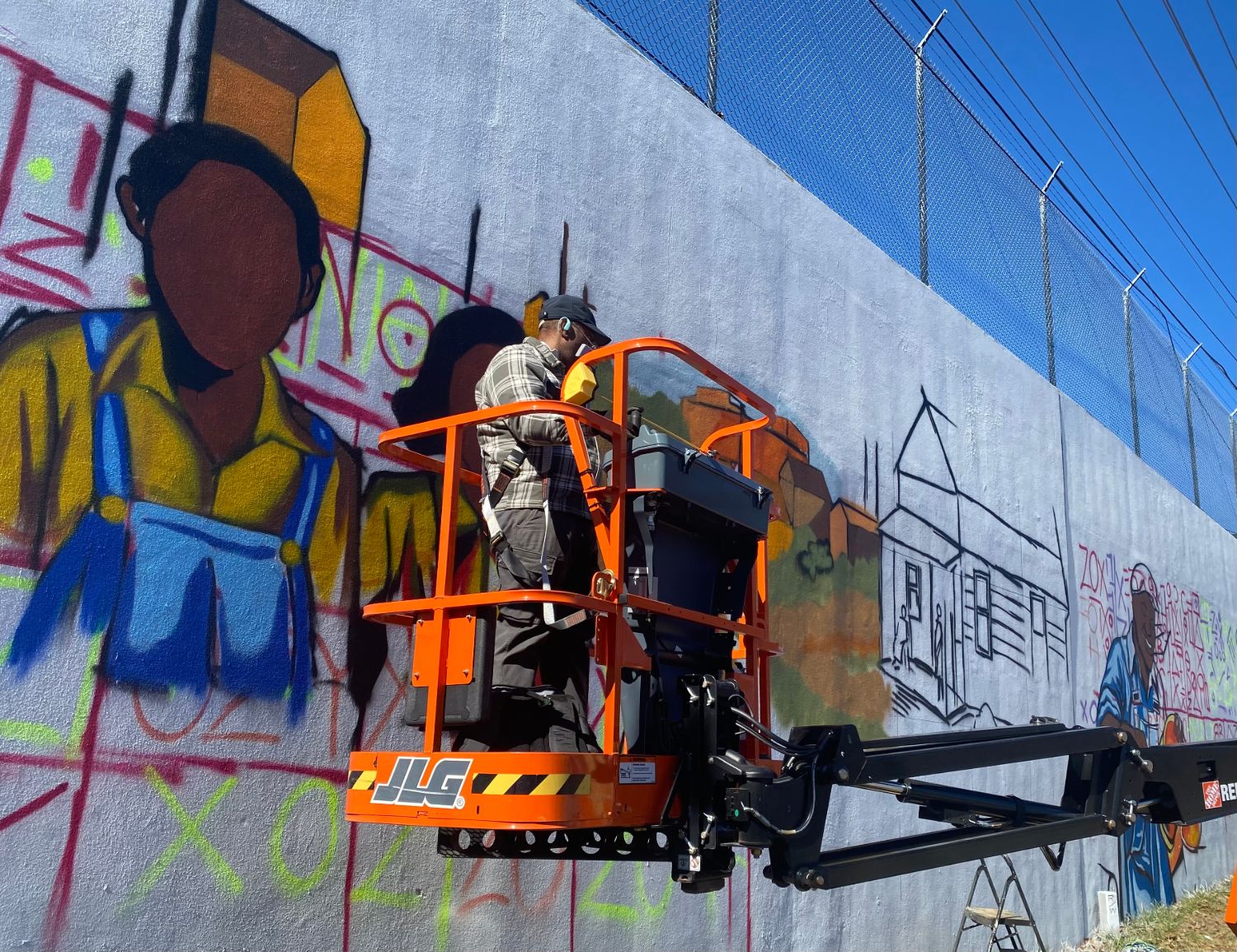 Atlanta muralist Corey Barksdale on a boom lift outlining figures for the Blandtown mural, work in progress
